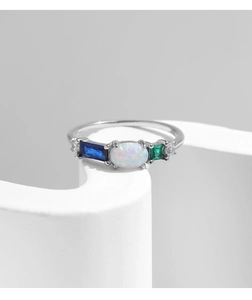 Detail of s925 silver ring featuring oval opal and emerald cut blue and green crystals