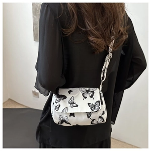 Rear view of model wearing a white butterfly print crossbody bag with wide shoulder strap