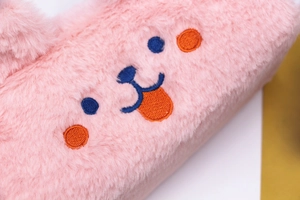 Close-up of pink plush pencil case featuring cute embroidered cartoon bear face detail