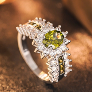 Makroaufnahme eines ovalen grünen Edelsteinrings mit weißem Zirkonia-Halo und Fassung