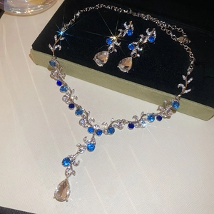 Detailed view of silver flower necklace and teardrop earrings with blue gemstones
