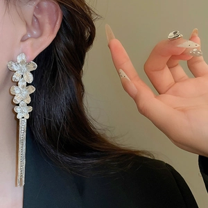 Detail of silver floral earrings with long tassels on model showing textured petals