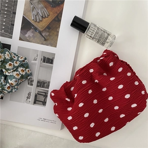 Flat lay of red polka dot ruffled fabric makeup bag with stylish lifestyle props