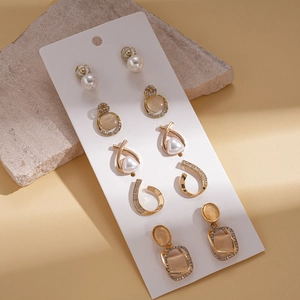 Detailansicht von fünf goldenen geometrischen Ohrringen mit Perlen und Strass auf Karte