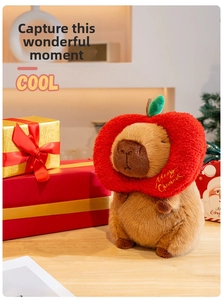 Close-up of plush Capybara with red apple hat and Merry Christmas gold embroidery