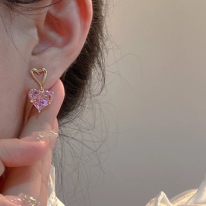 Close-up of heart-shaped gold stud earring with a dangling pink zircon stone for women