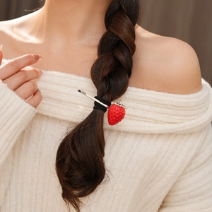 Primo piano di un elastico per capelli a fragola rossa su una treccia per uno stile chic