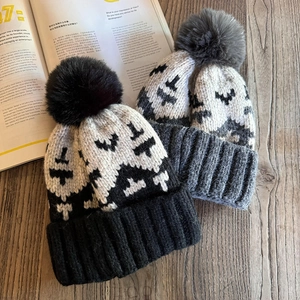 Retro pixel pattern knit beanies with fluffy pom poms on a natural wooden background