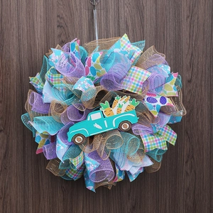 Easter wreath with blue truck and carrots on a dark wood wall background