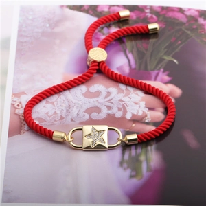 Adjustable red rope bracelet featuring a gold star charm paved with cubic zirconia stones