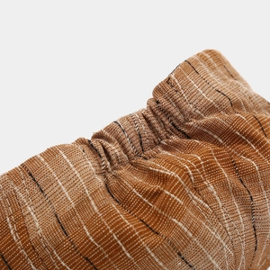 Détail macro du poignet élastique rayé sur une casquette vintage marron avec texture lin