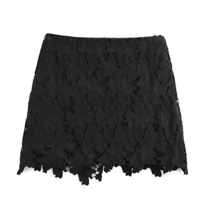 Dettaglio minigonna in pizzo nero con trama floreale traforata su sfondo bianco neutro