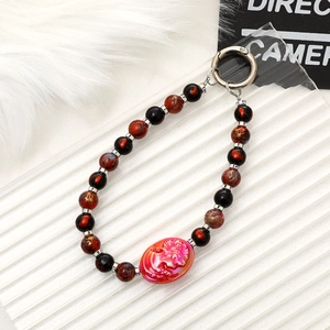 Detail of beaded phone strap with pink rose cameo and black glass beads on white background