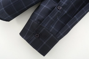 Dettaglio del polsino di una camicia a scacchi blu scuro con doppia chiusura a bottoni