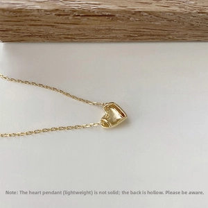 Detailed macro view of 18K gold heart necklace with lightweight hollow back design
