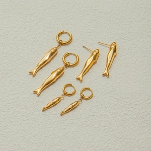 Detailed view of three pairs of golden hammered fish-shaped earrings on textured surface