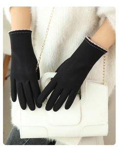 Detail of black suede winter gloves featuring decorative stitching and plaid lining cuff