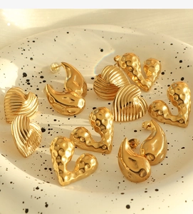 Detailed shot of golden heart and teardrop earrings with ribbed and hammered metal textures