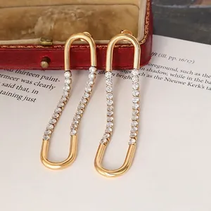 Chic U-shaped gold earrings with sparkling zircon stones displayed on a vintage red box