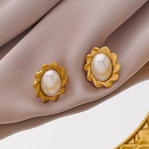Macro shot of vintage gold flower earrings with pearls on silk fabric background