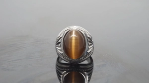 Macro shot of men's vintage steel ring featuring brown cat eye stone and engraved details