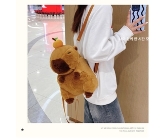 Cute Capybara plush backpack with orange accessory shown on a model side view