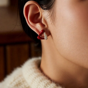 Gros plan de boucles d'oreilles cœur rouge plaquées or avec zircons portées