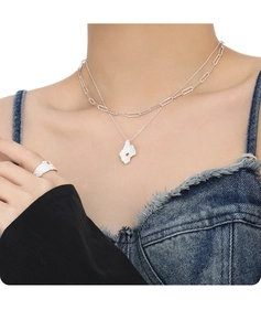 Detail of layered silver necklaces and textured ring featuring yellow stone accents