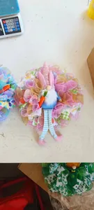 Détail d'une couronne de gnome de Pâques avec oreilles roses et jambes rayées à l'atelier