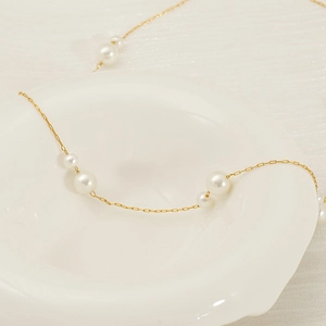 Minimalist gold-plated stainless steel bracelet featuring elegant white pearls on ceramic