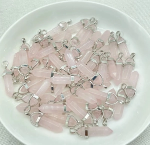 Detail of rose quartz hexagonal pendants with silver bails on beige linen background