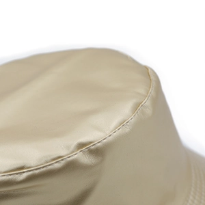 Macro shot of precise stitching on champagne gold faux leather bucket hat surface