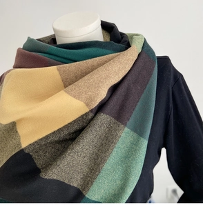 Detailed knit texture of a warm oversized plaid scarf in ginger and dark green tones