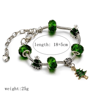 Détail d'un bracelet de Noël avec perles en verre vertes et breloques de fête