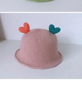 Detail of pink knitted baby bucket hat featuring cute orange and cyan heart ornaments