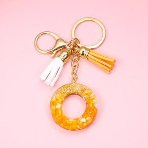 Detail of resin keychain with orange stones, gold flakes and colorful tassels