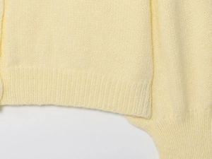 Detail of soft cream yellow knit cardigan showing ribbed hem and premium texture