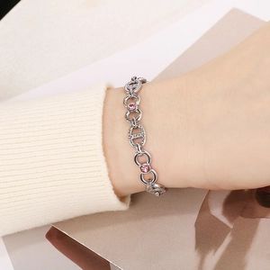 Silver bracelet with pink zircon stones and hollow D-shaped links on a white sweater