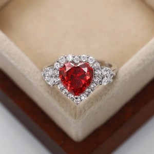 Macro shot of silver heart ring with red gemstone and sparkling accents in a jewelry box