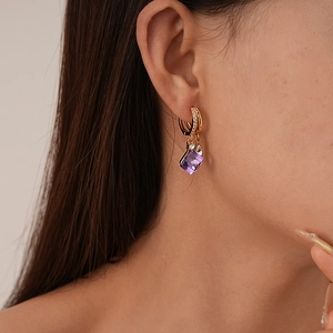 Dettaglio degli orecchini vintage in oro con cristallo viola e zirconi indossati da modella