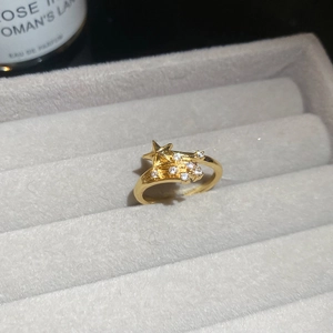 Detail shot of a golden star ring with zircon stones in a gray velvet jewelry box