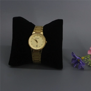 Macro detail of a gold quartz watch with metal strap on a black velvet display pillow