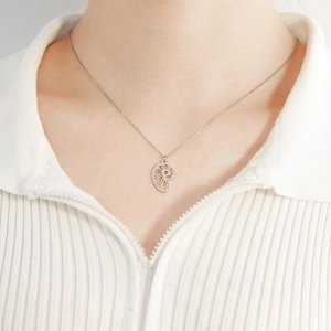 Détail du collier avec pendentif nautile argenté porté sur un col de chemise blanc
