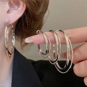 Boucles d'oreilles créoles géométriques en argent en trois tailles portées par un mannequin