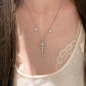 Detailed close-up of a stainless steel zircon key necklace with star and heart charms