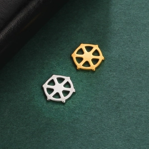 Macro shot of gold and silver hexagonal hollow jewelry pendants on green texture