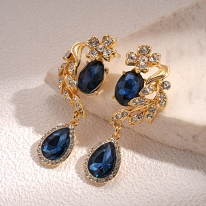 Detailed close-up of vintage flower earrings with blue teardrop gems and gold metal base