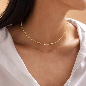 Detailed close-up of a gold star choker necklace worn with a white professional shirt