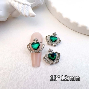 Macro shot of a vintage crown nail charm with a green heart gem and silver frame