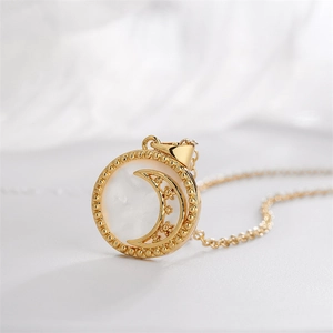 Gold round pendant necklace with shell inlay featuring moon and star motifs on white fabric